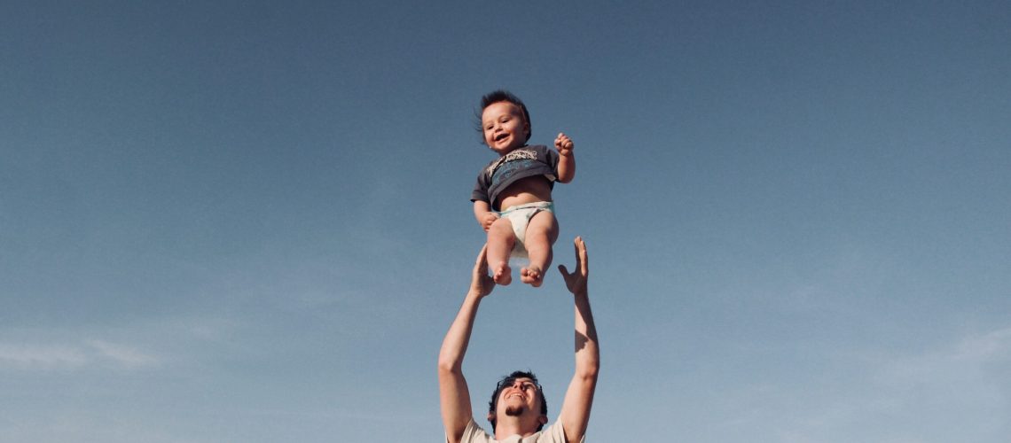 photo-of-man-in-raising-baby-under-blue-sky-1166990